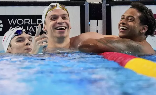 Leon Marchand of France, center, celebrates after winning gold medal in the men's 200-meter individual medley final at the World Aquatics Championships in Singapore, Thursday, July 31, 2025. (AP Photo/Vincent Thian)