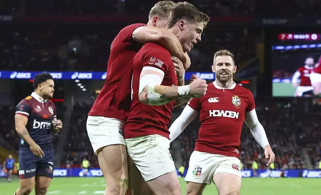 Tommy Freeman, centre, of the British &amp; Irish Lions is congratulated by teammates' Duhan van der Merwe and Elliot Daly, right, after scoring his team's first try during their game against the Queensland Reds in Brisbane, Australia, Wednesday, July 2, 2025. (AP Photo/Pat Hoelscher)