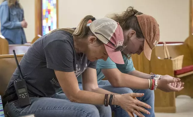 Ginger Turner, and her daughter, Hailey, right, pray during church services held at the Hunt Baptist Church on Sunday, July 6, 2025, in Hunt, Texas. Their small town sits on the bank of the Guadalupe River and was severely damaged by recent flooding. (AP Photo/Rodolfo Gonzalez)
