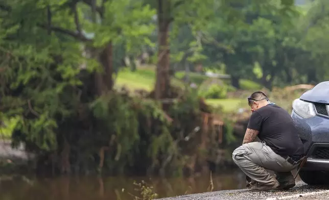 Avi Santos, 23, of San Antonio, Texas, reacts while stopping on the road alongside at Camp Mystic along the banks of the Guadalupe River after a flash flood swept through the area Sunday, July 6, 2025, in Hunt, Texas. (AP Photo/Julio Cortez)