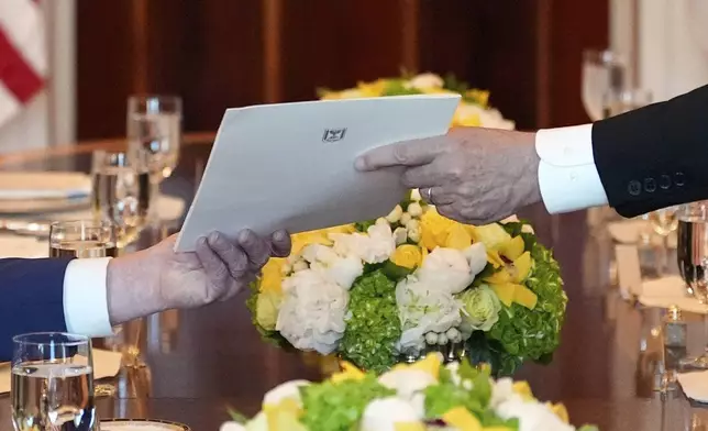 Israel's Prime Minister Benjamin Netanyahu, right, hands President Donald Trump a folder during a meeting in the Blue Room of the White House, Monday, July 7, 2025, in Washington. (AP Photo/Alex Brandon)