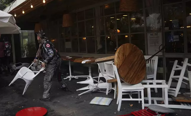 A demonstrator tosses a restaurant chair at the end of peaceful protest that turned violent against gentrification, as the increase in remote workers has risen prices and increased housing demand in neighborhoods like Condesa and Roma, in Mexico City, Friday, July 4, 2025. (AP Photo/Aurea Del Rosario)