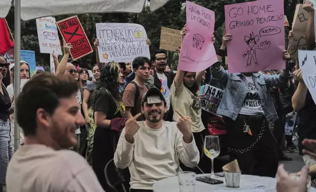 A man points to his Mexican ID to prove his nationality as people protest against gentrification, as the increase in remote workers has risen prices and increased housing demand in neighborhoods like Condesa and Roma, in Mexico City, Friday, July 4, 2025. (AP Photo/Jon Orbach)