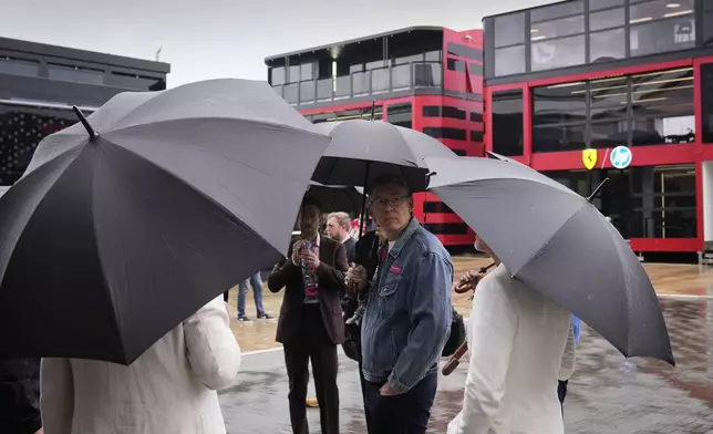 Visitors in the paddock stand under umbrellas during a shower at the Silverstone racetrack ahead of the British Formula One Grand Prix, in Silverstone, England, Sunday, July 6, 2025.(AP Photo/Darko Bandic)