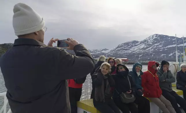 Tourists on a whale watching boat tour take photos at sea near Nuuk, Greenland, Tuesday, June 17, 2025. (AP Photo/Kwiyeon Ha)