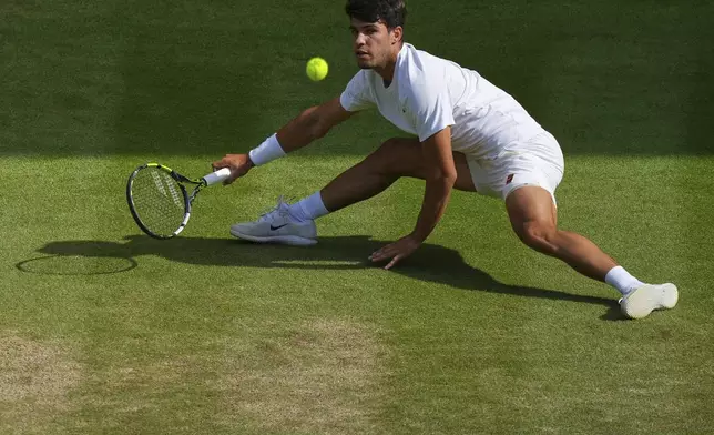 Carlos Alcaraz of Spain slips as he returns a shot by Italy's Jannik Sinner in the men's singles final at the Wimbledon Tennis Championships in London, Sunday, July 13, 2025. (AP Photo/Joanna Chan)