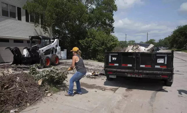 A volunteer removes tree debris from a flood-damaged home on Guadalupe Street in Kerrville, Texas, on July 12, 2025. (AP Photo/Gabriela Aoun Angueira)