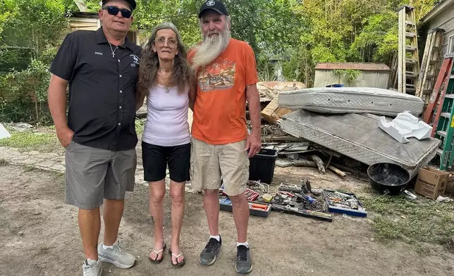 Colleen Lucas, center, and her husband, Dave, right, stand outside their flood-destroyed home in Ingram, Texas, with Lucas' son John Vinyard, on Friday, July 11, 2025. (AP Photo/Gabriela Aoun Angueira)
