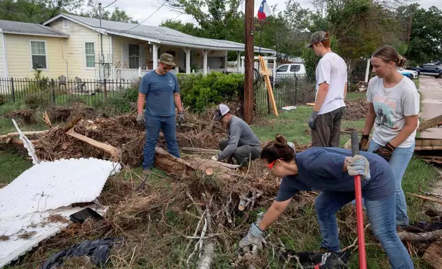 Volunteers from Kerrville Bible Church saw and haul tree debris in front of a flood-damaged home on Guadalupe Street in Kerrville, Texas, on Saturday, July 12, 2025. (AP Photo/Gabriela Aoun Angueira)