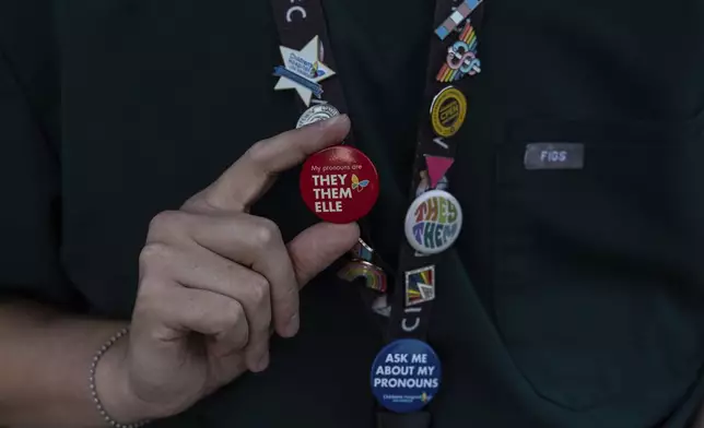 Jack Brenner, left, an emergency room nurse at Children's Hospital Los Angeles, shows a lanyard decorated with pronoun pins and buttons during a protest against the closure of the hospital's trans youth clinic Thursday, July 3, 2025, in Los Angeles. (AP Photo/Jae C. Hong)