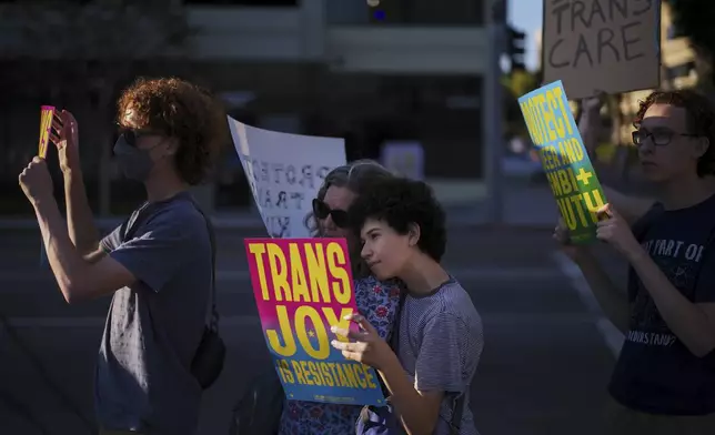 Lindsey Nelson, center left, and her son, Max Deiner, take part in a protest against the closure of the trans youth clinic at Children's Hospital Los Angeles, Thursday, July 3, 2025, in Los Angeles. (AP Photo/Jae C. Hong)