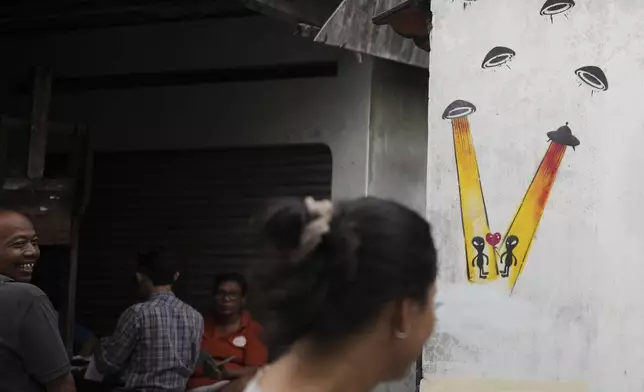 An alien-themed mural is seen on the facade of a grocery store at a neighborhood colloquially known as a "UFO Village" in Yogyakarta, Indonesia, Thursday, July 24, 2025. (AP Photo/Dita Alangkara)