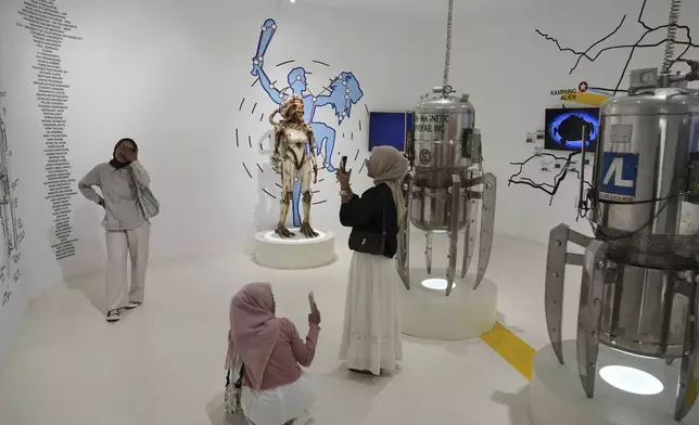 Visitors take photos near an alien figure displayed at an exhibition on the side line of the Indonesia UFO Festival, in Yogyakarta, Indonesia, Thursday, July 24, 2025. (AP Photo/Dita Alangkara)