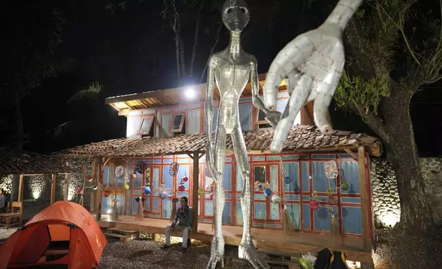 Local artist Hangno Hartono sits near an alien figure during the Indonesia UFO Festival, in Yogyakarta, Indonesia, Thursday, July 24, 2025. (AP Photo/Dita Alangkara)