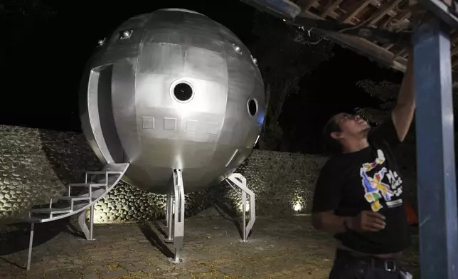 A worker set up a lighting to illuminate a conceptual Mars exploration module during the "UFO Camp" at the Indonesia UFO Festival in Yogyakarta, Indonesia,Thursday, July 24, 2025. (AP Photo/Dita Alangkara)