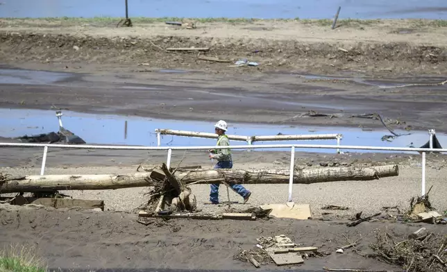 A man crosses the Ruidoso Downs Racetrack which was partially destroyed after the flood, Wednesday, July 9, 2025, in Ruidoso, N.M. (AP Photo/Roberto E. Rosales)