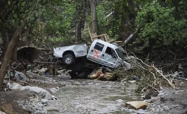 A damaged truck is seen on the banks of the river in Ruidoso, N.M. Wednesday, July 9, 2025, a day after major flooding washed away properties and Rv's along the Rio Ruidoso Tuesday afternoon. (AP Photo/Roberto E. Rosales)