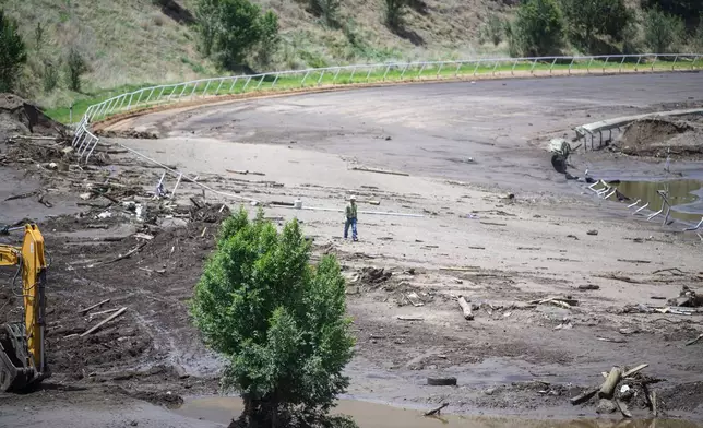 A man crosses the Ruidoso Downs Racetrack which was partially destroyed after the flood, Wednesday, July 9, 2025, in Ruidoso, N.M. (AP Photo/Roberto E. Rosales)