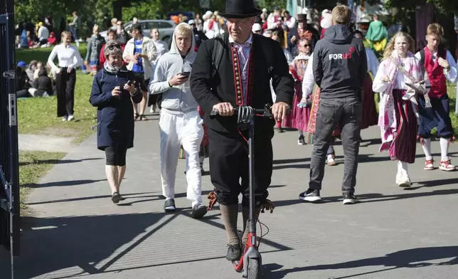 A participant rides a scooter ahead of the Estonian Song and Dance Celebration "Iseoma" at the Kalev Stadium in Tallinn, Estonia, Friday, July 4, 2025. (AP Photo/Sergei Grits)