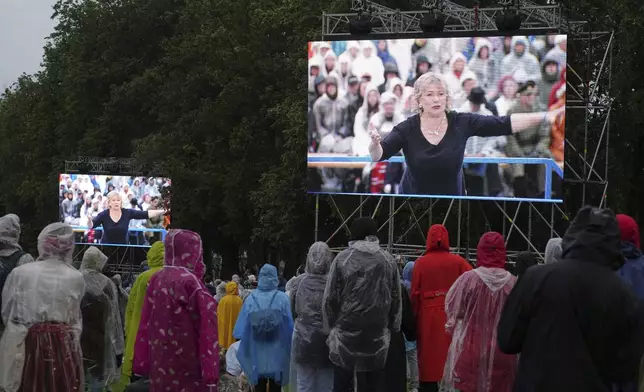 Artistic director of the Song Celebration Heli Jurgenson, seen on the screens, attending the Estonian Song Festival, part of the "Iseoma" Song and Dance Celebration, at the Song Festival Grounds in Tallinn, Estonia, Saturday, July 5, 2025. (AP Photo/Sergei Grits)