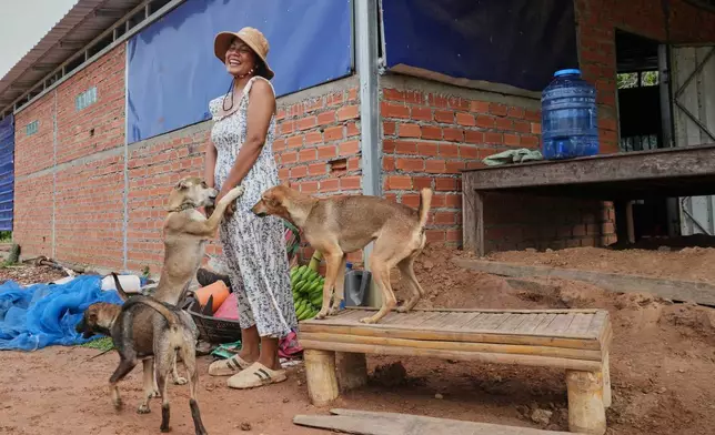 Cambodian woman, Soklang Sareoun, 28, greets her dogs she returns home after five days in Prasat Roboeuk village, Oddar Meanchey province, Cambodia, Tuesday, July 29, 2025, after a ceasefire was supposed to take effect Monday night between Thailand and Cambodia. (AP Photo/Heng Sinith)