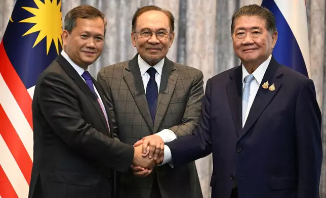 Malaysia's Prime Minister Anwar Ibrahim, center, Cambodia's Prime Minister Hun Manet left and Thailand's acting Prime Minister Phumtham Wechayachai pose for photos after talks on a possible ceasefire between Thailand and Cambodia in Putrajaya, Malaysia, Monday, July 28, 2025. (Mohd Rasfan/Pool Photo via AP)
