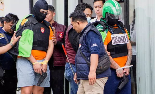 Australian nationals identified by initials as PT, left, and MC, the suspects in the fatal shooting of an Australian tourist in June, take part in a police reenactment in Badung, Bali, Indonesia on Wednesday, July 30, 2025. (AP Photo/Firdia Lisnawati)
