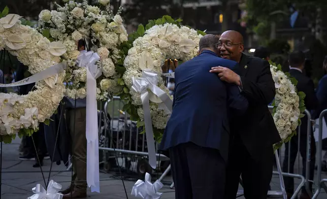 People embrace before a vigil for the four people killed in the previous day's shooting at 345 Park Avenue, including NYPD officer Didarul Islam, in Bryant Park, Tuesday, July 29, 2025, in New York. (AP Photo/Angelina Katsanis)