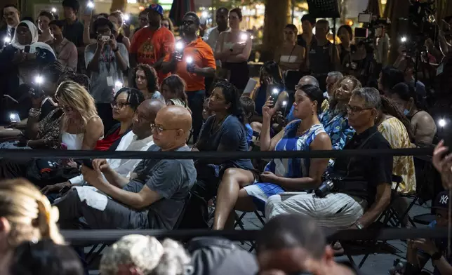 People raise their phone lights during the vigil for the victims killed in the previous day's shooting at 345 Park Avenue, including NYPD officer Didarul Islam, in Bryant Park, Tuesday, July 29, 2025, in New York. (AP Photo/Angelina Katsanis)