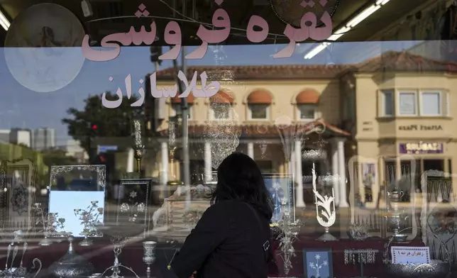 A woman looks into the window of a store selling Persian souvenirs in the "Tehrangeles" neighborhood of Los Angeles Tuesday, June 24, 2025. (AP Photo/Jae C. Hong)
