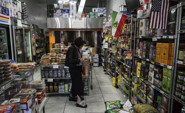 A woman shops at a grocery store decorated with American and Iranian flags in the "Tehrangeles" neighborhood of Los Angeles Tuesday, June 24, 2025. (AP Photo/Jae C. Hong)