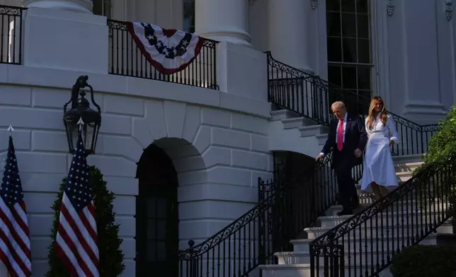 President Donald Trump and first lady Melania Trump walk down the steps from the Blue Room Balcony to sign his signature bill of tax breaks and spending cuts at the White House, Friday, July 4, 2025, in Washington. (AP Photo/Julia Demaree Nikhinson)