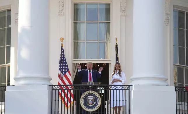 President Donald Trump speaks from the Blue Rom Balcony as first lady Melania Trump listens before he signs his signature bill of tax breaks and spending cuts at the White House, Friday, July 4, 2025, in Washington. (AP Photo/Evan Vucci)