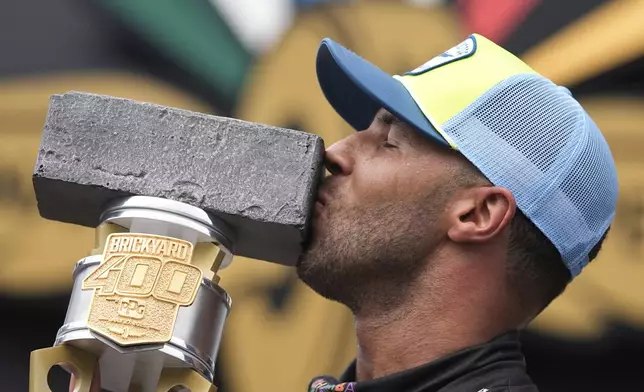 Bubba Wallace kisses the trophy after winning a NASCAR Cup Series auto race at Indianapolis Motor Speedway, Sunday, July 27, 2025, in Indianapolis. (AP Photo/Darron Cummings)