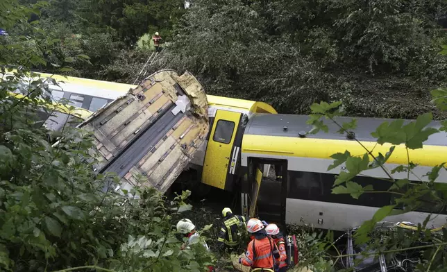Rescue workers search for passengers in a derailed train, Zwiefaltendorf, Sunday July 27, 2025. (Thomas Warnack/dpa via AP)