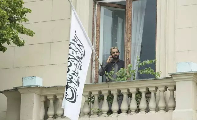 A man talks by a phone while standing on a balcony of the Afghan Embassy in Moscow, Russia, Friday, July 4, 2025, where the flag of the Islamic Emirate of Afghanistan was raised after Russia recognized the Taliban government in Afghanistan. (AP Photo/Pavel Bednyakov)