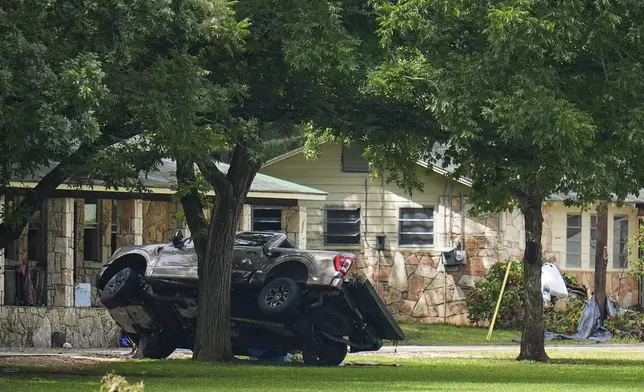 A truck rests on a tree outside sleeping quarters at Camp Mystic along the banks of the Guadalupe River after a flash flood swept through the area Saturday, July 5, 2025, in Hunt, Texas. (AP Photo/Julio Cortez)