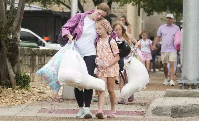 A woman and a child embrace after girls from Camp Waldemar, near the North fork of the Guadalupe River, are reunited with their families after heavy rainfall in Central Texas, Saturday, July 5, 2025. (Jason Fochtman/Houston Chronicle via AP)