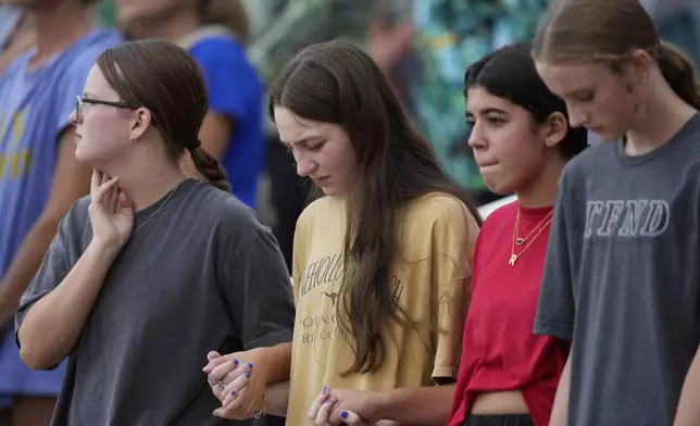 Attendees hold hands during a vigil for flooding victims at Tivy Antler Stadium on Wednesday, July 9, 2025, in Kerrville, Texas. (AP Photo/Ashley Landis)