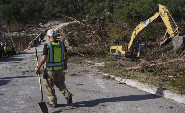 Crews work on the Cade Loop Bridge to clear debris following flooding, Thursday, July 10, 2025, in Ingram, Texas. (AP Photo/Joshua A. Bickel)