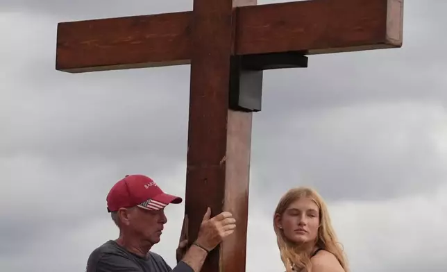 Dan Beazley, of Michigan, left, and Abigail Smithson hold a large cross during a vigil for flooding victims at Tivy Antler Stadium on Wednesday, July 9, 2025, in Kerrville, Texas. (AP Photo/Gerald Herbert)