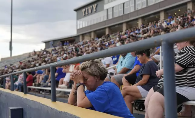 A woman prays during a vigil for flooding victims at Tivy Antler Stadium on Wednesday, July 9, 2025, in Kerrville, Texas. (AP Photo/Ashley Landis)