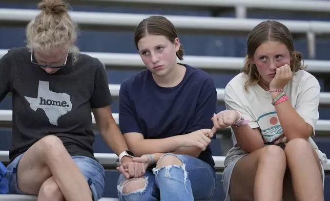 Attendees hold hands during a vigil for flooding victims at Tivy Antler Stadium on Wednesday, July 9, 2025, in Kerrville, Texas. (AP Photo/Ashley Landis)