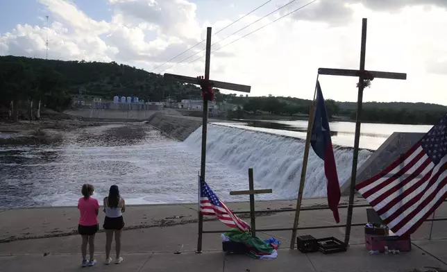 Bethiane Miller, left, of Kerrville, and her daughter Samantha visit a memorial for flood victims next to the Guadalupe River on Thursday, July 10, 2025, in Kerrville, Texas. (AP Photo/Gerald Herbert)