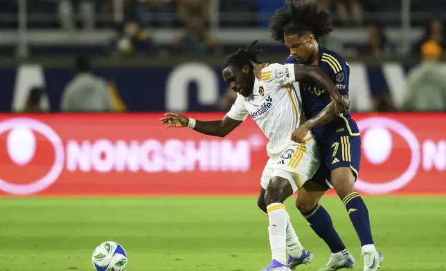 Los Angeles Galaxy forward Joseph Paintsil, left, and Vancouver Whitecaps forward Jayden Nelson vie for the ball during the second half of an MLS soccer match Friday, July 4, 2025, in Carson, Calif. (AP Photo/William Liang)