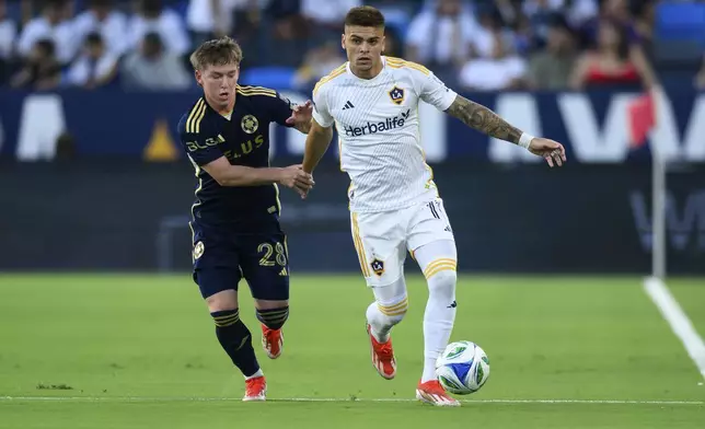Los Angeles Galaxy forward Gabriel Pec, right, controls the ball while under pressure from Vancouver Whitecaps defender Tate Johnson (28) during the first half of an MLS soccer match Friday, July 4, 2025, in Carson, Calif. (AP Photo/William Liang)