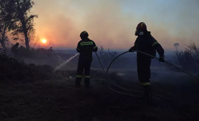 Firefighters try to extinguish a wildfire, in the northwestern suburb of Kryoneri, in Athens, Greece, Saturday, July 26, 2025. (AP Photo/Yorgos Karahalis)