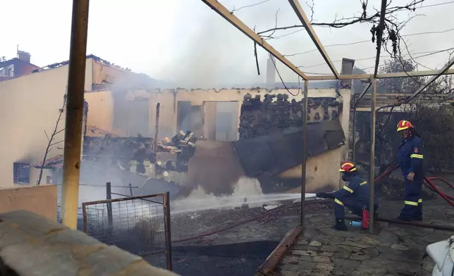 Firefighters try to extinguish a fire at a house during a wildfire, in the northwestern suburb of Kryoneri, in Athens, Greece, Saturday, July 26, 2025. (AP Photo/Yorgos Karahalis)