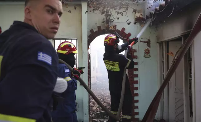 Firefighters try to extinguish the blazes at a house during a wildfire, in the northwestern suburb of Kryoneri, in Athens, Greece, Saturday, July 26, 2025. (AP Photo/Yorgos Karahalis)