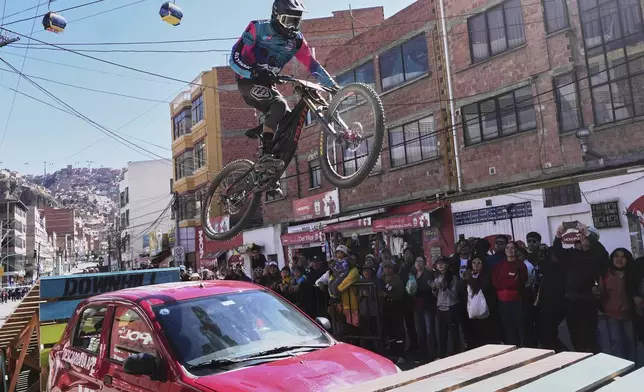 A competitor rides over a car during the Challenge Downhill mountain bike race in La Paz, Bolivia, Sunday, July 6, 2025. (AP Photo/Juan Karita)